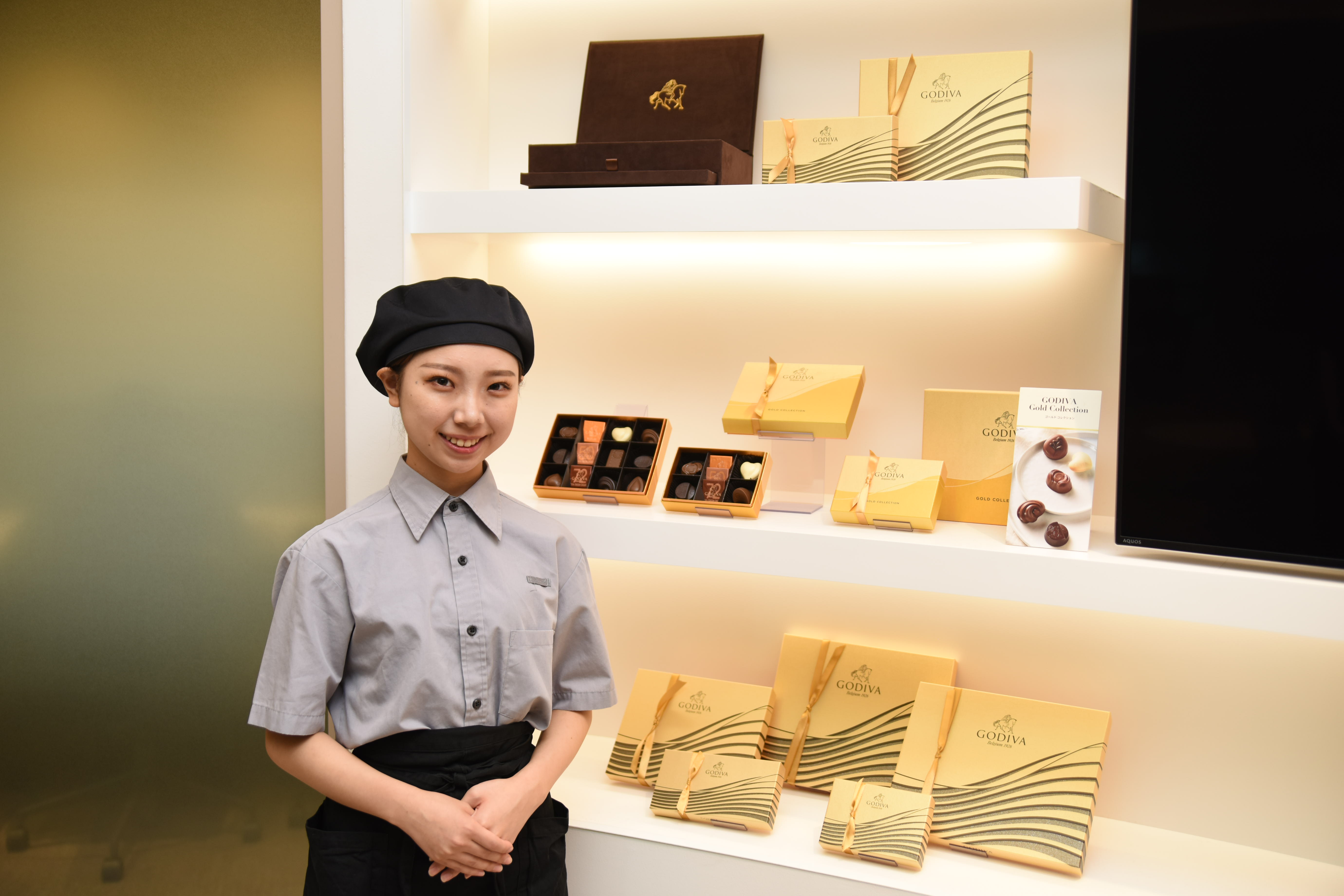 ゴディバの商品の前で微笑む女性店員
