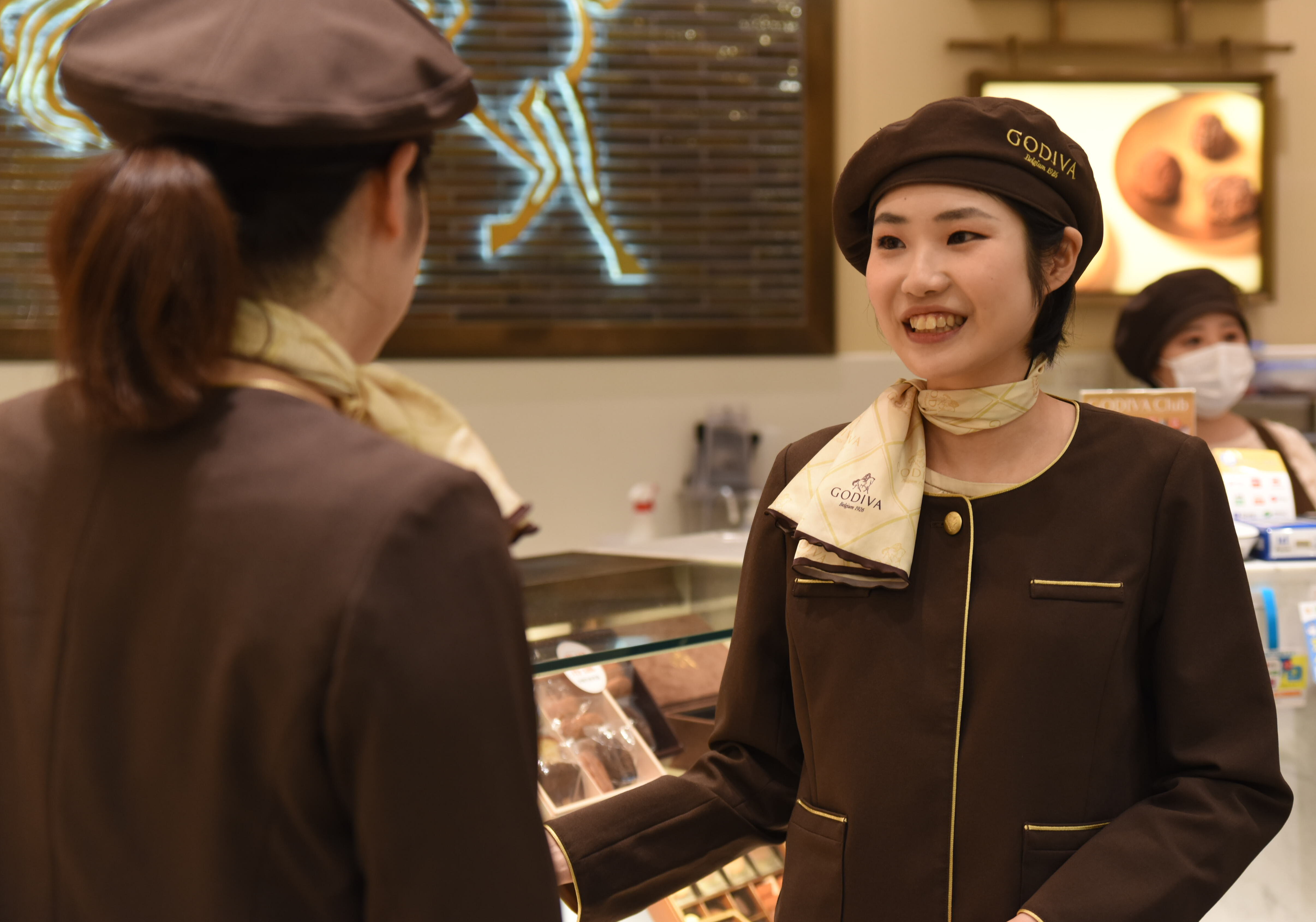 GODIVAの店舗で店員と会話する女性店員